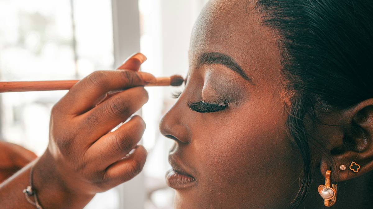 Close-up of model applying strong hold setting gel to brushed-up eyebrows with precision wand